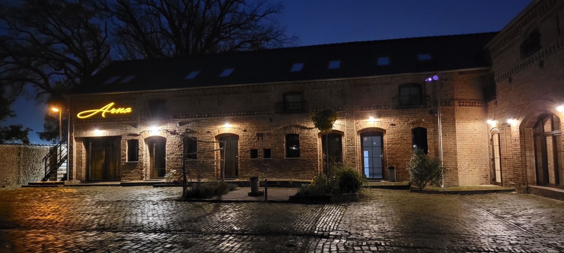 ARNO Monteurunterkunft – Historisches Backsteingebäude bei Nacht mit beleuchtetem ARNO-Schriftzug