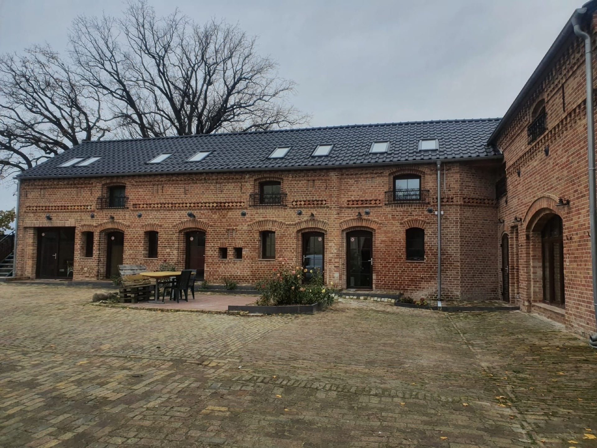 Innenhof der ARNO Monteurunterkunft bei Tag, mit Backsteingebäude und Sitzgelegenheiten